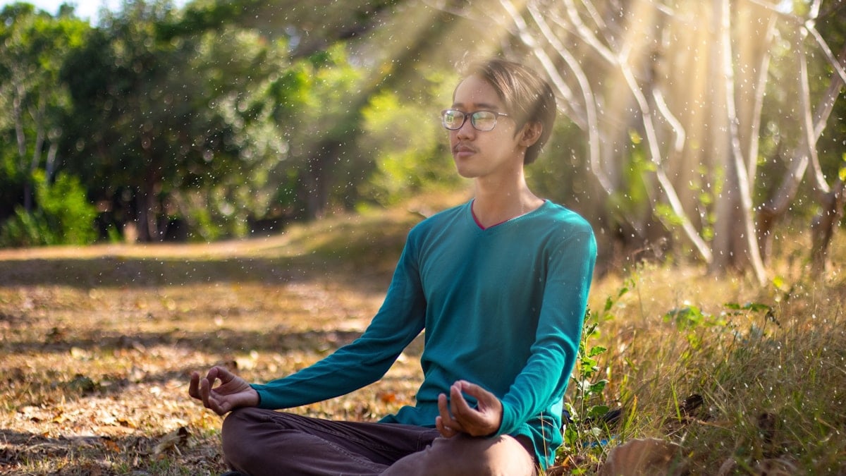 A man is doing a meditation on the grass